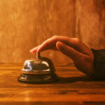 Businesswoman ringing hotel reception bell Businesswoman ringing hotel reception bell, warm retro toned image with selective focus